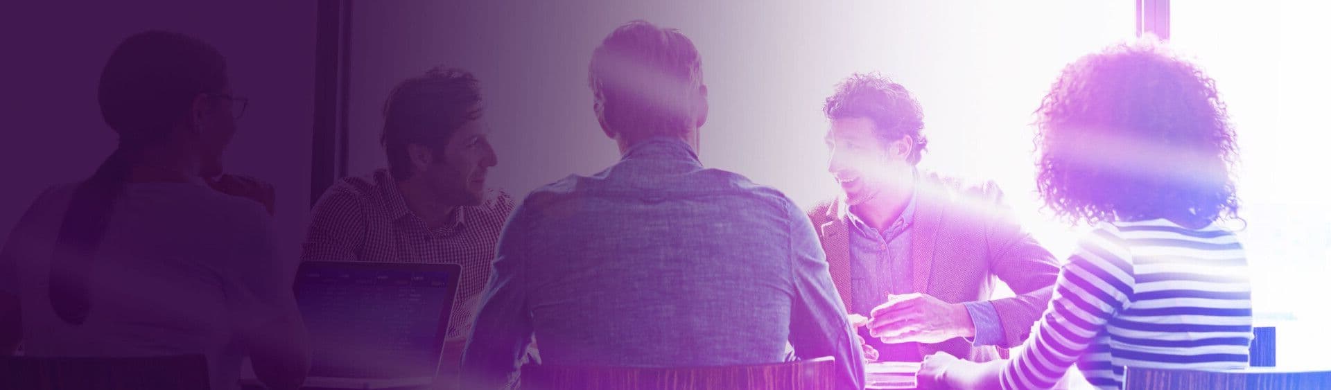 Colleagues in a meeting, seen from behind, with a bright purple and pink light overlay.